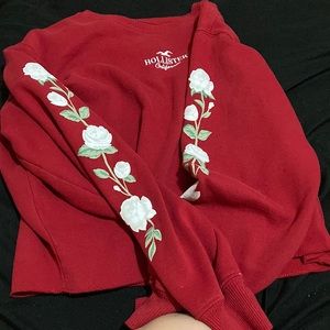 Red sweater, flowers on both arms going down the sleeves